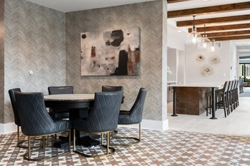 a dining area with a table and chairs and a kitchen in the background